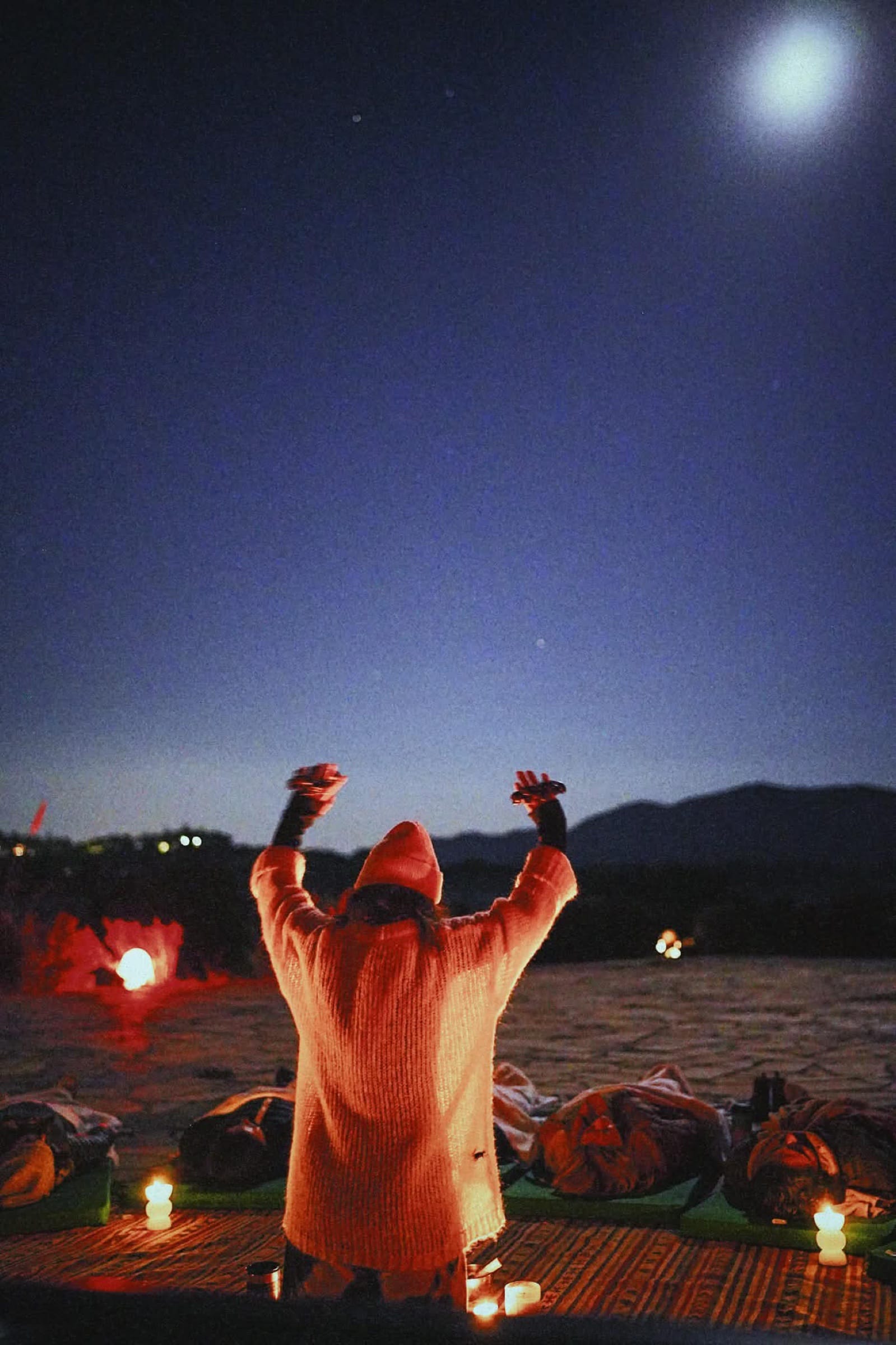 Arms raised to a full moon at a night ceremony