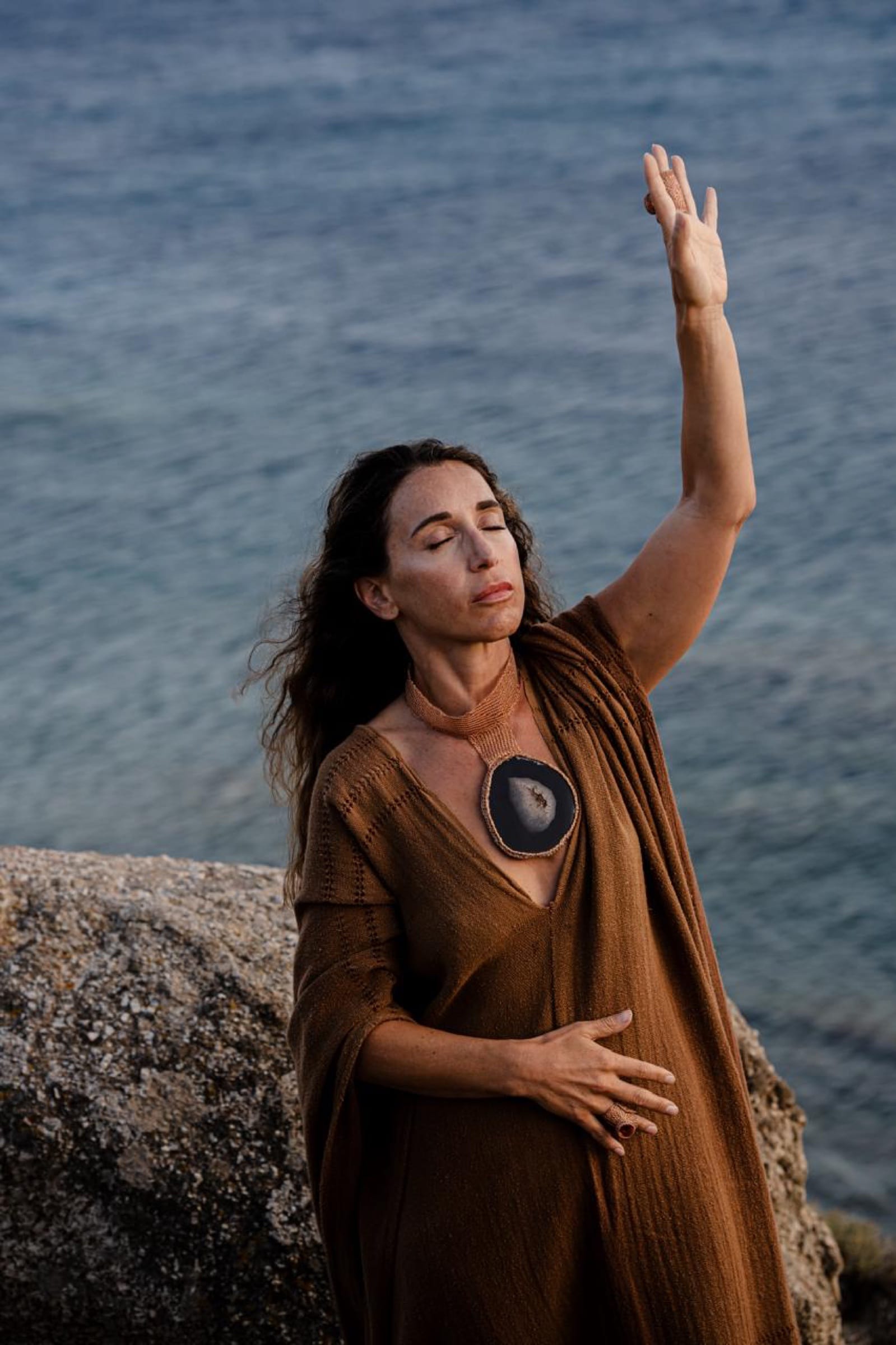 One hand raised over the sea, the other at my heart