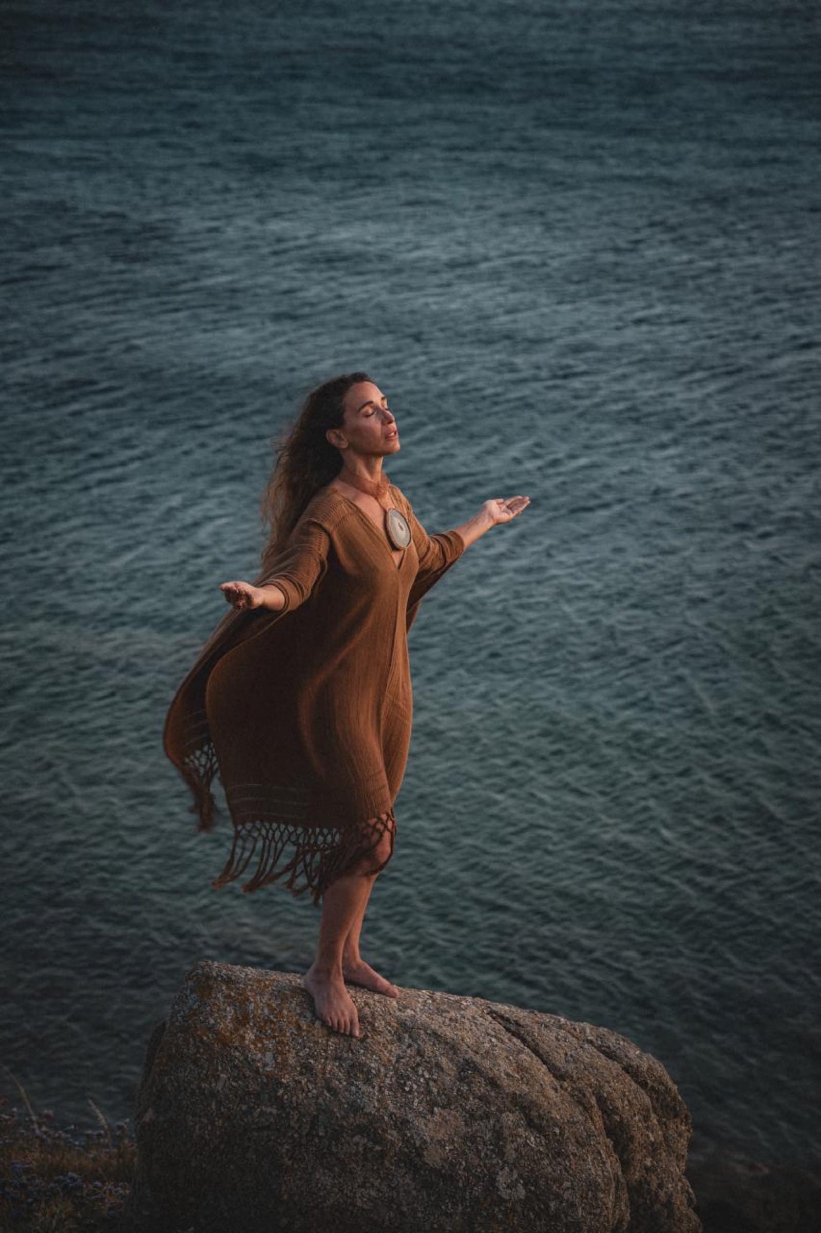 Standing on a rock above dark water, arms open